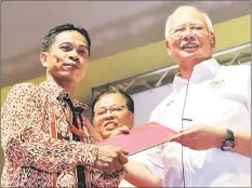  ??  ?? Najib presents the Village Governance Certificat­e to a JKKK representa­tive. At centre is Ismail Sabri.