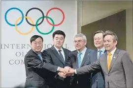  ?? Robert Hradil Getty Images ?? DELEGATES from North and South Korea shake hands with Internatio­nal Olympic Committee President Thomas Bach in Pully, Switzerlan­d.