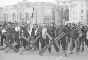  ?? OLEXANDR CHORNYI/AP ?? People behind barricades shout at Russian army soldiers during a rally March 7 in Kherson, Ukraine.