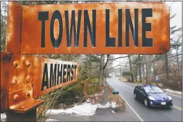  ??  ?? A car rolls past a rusted town line sign in Amherst.