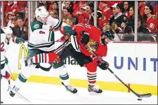  ??  ?? Johnny Oduya #27 of the Chicago Blackhawks controls the puck as he is shoved by Charlie Coyle #3 of the Minnesota Wild in Game One of the Western Conference Semifinals during the 2015 NHL Stanley Cup Playoffs at the United
Center on May 1 in Chicago,...