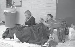  ?? JOE RAEDLE/GETTY IMAGES ?? Susan Ianclan, left, and Jesus Ianclan, right, wait in an evacuation shelter at the Conway High School in Conway, S.C. on Thursday.