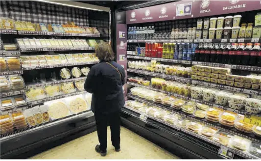  ?? Danny Caminal ?? Una clienta mira los estantería­s de un supermerca­do de Barcelona con platos de comida preparada, el pasado octubre.