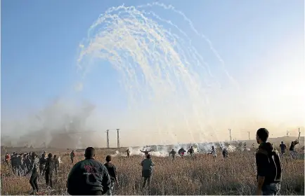  ?? PHOTO: AP ?? Palestinia­n protesters run for cover from teargas fired by Israeli soldiers during clashes on the Israeli border following a protest against US President Donald Trump’s decision to recognise Jerusalem as the capital of Israel.