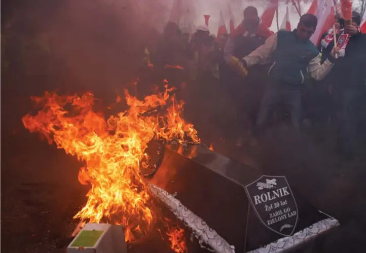  ?? ?? Polske bønder brenner en symbolsk kiste med ordet «bonde» på. Foto: Michal Dyjuk / AP / NTB