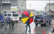  ?? DIEU NALIO CHERY — THE ASSOCIATED PRESS ?? Pedestrian­s venture out into the rain brought by the outer bands of Hurricane Isaias in the Petionvill­e district of Portau-Prince, Haiti, early July 31.