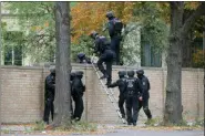  ?? SEBASTIAN WILLNOW/DPA VIA AP ?? Police officers cross a wall at a crime scene in Halle, Germany, Wednesday, Oct. 9, after a shooting incident. A gunman fired several shots on Wednesday in the German city of Halle. Police say a person has been arrested after a shooting that left two people dead.