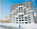  ?? (Baz Ratner/Reuters) ?? AN ULTRA-ORTHODOX youth walks past a constructi­on site in Modi’in Illit.