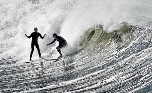  ?? IAIN McGREGOR/STUFF ?? Sam Loader, left, gets dropped in on while surfing. Some groups at Sumner say this is an increasing problems at the surf spot due to increased numbers of paddle boarders.