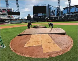  ?? CURTIS COMPTON / CCOMPTON@AJC.COM ?? Braves field managers Anthony DeFeo (left) and Tyler Lenz work at Truist Park in April. MLB still hasn’t determined when, or if, the season will start.