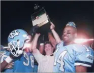  ?? HANS DERYK - THE ASSOCIATED PRESS ?? FILE - In this Dec. 30, 1995, file photo, North Carolina head coach Mack Brown hoists the trophy in the air as he’s surrounded by players Eric Thomas(38) and Marcus Wall (14) after they defeated Arkansas 20-10in the Carquest Bowl NCAA college football game in Miami.