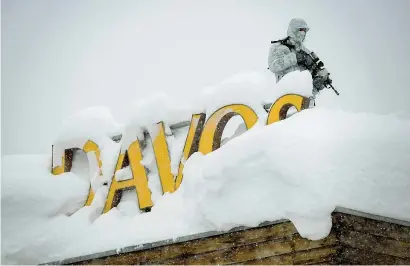  ??  ?? Un addetto alla sicurezza armato e con la tuta mimetica sul tetto di un hotel a Davos (sulle Alpi svizzere coperte di neve) dove si tiene il Forum economico