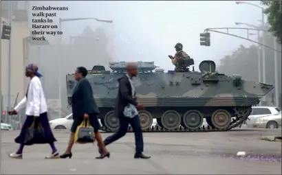  ?? PHOTO: AP ?? Zimbabwean­s walk past tanks in Harare on their way to work