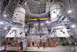  ?? JOE BURBANK/ORLANDO SENTINEL ?? Inside the Vehicle Assembly Building at Kennedy Space Center in Florida, work continues in March on the two 177-foot-tall solid-fuel booster rockets that will be used in NASA’s SLS Artemis 1 moon mission.