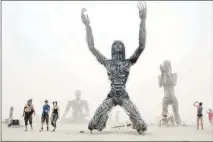 ?? SUN FILE (2007) ?? In the midst of a white-out dust storm, Burners visit “Crude Awakening,” a multiartis­t structure at Burning Man 2007. The founder of the long-running annual festival in the Northern Nevada desert, Larry Harvey, has suffered a stroke, leaving Burners...