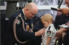  ??  ?? Toddler Harvey Keaton receives his father’s posthumous medal from fire chief Shane Fitzsimmon­s