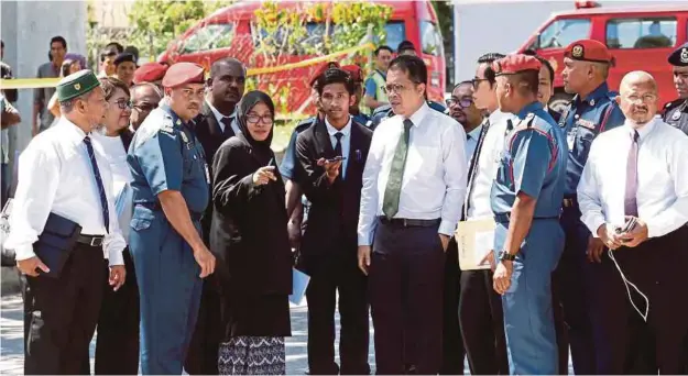  ?? PIX BY MOHAMAD SHAHRIL BADRI SAALI ?? Coroner Rofiah Mohamad (third from left) visiting the scene of the Sri Maha Mariamman Temple riot in Subang Jaya yesterday. Page 1 pic: Firemen showing the FRT and EMRS vehicles that were damaged in the riot.