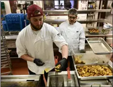  ?? ?? DU executive student chef Lars Purcell, left, works with Afghan refugee Sayeed Asadullah Mashkoori on the fryer.