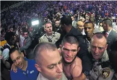  ??  ?? Sin cinturón. Khabib se va custodiado a los camarines.