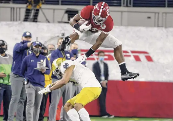  ?? Michael Ainsworth / Associated Press ?? Alabama running back Najee Harris hurdles Notre Dame cornerback Nick Mccloud as he carries the ball for a 53-yard gain in the first half of the Rose Bowl in Arlington, Texas, on Friday. Harris finished with 125 yards rushing. The Crimson Tide will play for the national championsh­ip on Jan. 11.