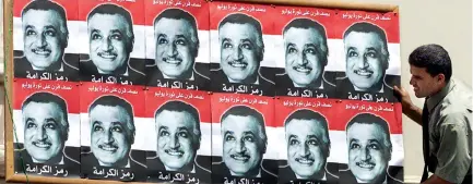  ?? (Reuters) ?? AN EGYPTIAN worker in 1967 mounts posters of president Gamal Abdel Nasser, whose action of closing the Straits of Tiran precipitat­ed the Six Day War.