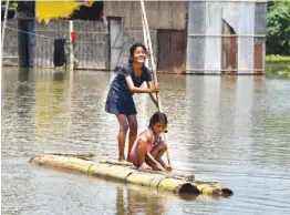  ?? — PTI ?? Children use a makeshift raft to cross a flood-affected area after heavy monsoon rain, in Morigaon district, Assam, on Tuesday.