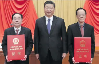  ??  ?? Chinese President Xi Jinping (middle) poses for a photo with explosives expert Wang Zeshan (right) and virologist Hou Yunde, winners of China’s top science award, at the National Science and Technology Award Conference in Beijing, China.