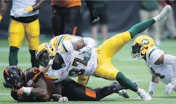  ?? THE CANADIAN PRESS ?? Lions running back Jeremiah Johnson, who galloped for 108 yards on 17 carries, protects the ball as he’s tackled by Eskimos defensive back Kenny Ladler.