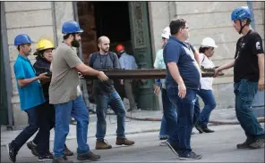  ?? AP/SILVIA IZQUIERDO ?? Brazilian firefighte­rs and museum workers carry away a painting Monday after it burned during the fire at the National Museum in Rio de Janeiro.