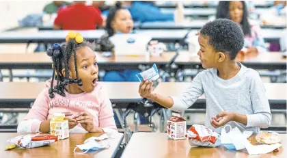  ?? ANDREW RUSH/AP ?? First graders Kendal Kates, left, and Ryan Kenney are excited about the contents of their lunches at Langley K-8 School on Dec. 23 in the Sheraden neighborho­od in Pittsburgh. COVID-19 has hindered access to free and subsidized school meals.