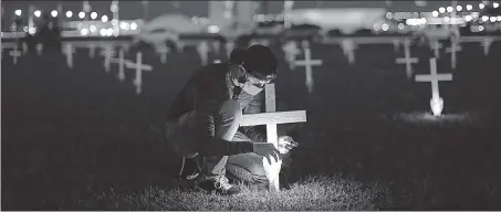  ?? REUTERS ?? A man lights a candle next to a cross symbolisin­g the ones who died from the coronaviru­s disease, in front of the National Congress in Brasilia, Brazil.