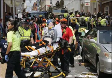  ?? STEVE HELBER — THE ASSOCIATED PRESS FILE ?? Rescue personnel help injured people who were hit when a car ran into a large group of protesters after a white nationalis­t rally in Charlottes­ville, Va.