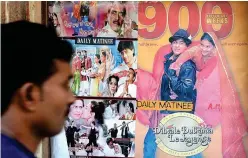  ?? File/agence France-presse ?? A cinemagoer walks past a poster of the Bollywood film ‘Dilwale Dulhania Le Jayenge’ in Mumbai.