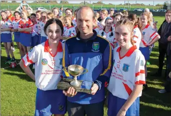  ??  ?? Aughrim/Annacurra joint captains Hannah Doyle and Shauna O’Shea are presented with the Under-14 Camogie Championsh­ip trophy by Wicklow Camogie chairman Serge Goetelen.