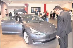  ?? STAFF FILE PHOTO ?? People check out the Tesla Model 3 at the electric sedan’s first appearance in a Tesla showroom in January at Stanford Shopping Center in Palo Alto.