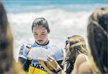  ?? Callaghan O’Hare Los Angeles Times ?? MEAH COLLINS signs autographs after finishing third in a three-women, first-round heat at the U.S. Open of Surfing in Huntington Beach. The 16-year-old is competing Tuesday to continue in the event.