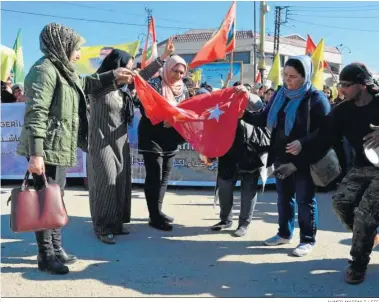  ?? AHMED MARDNLI / EFE ?? Unas mujeres kurdas queman ayer una bandera turca en Qamishli, en el norte de Siria.