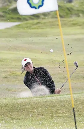  ??  ?? COLD AND WET: Kelsey Macdonald splashes it out of a bunker on the 17th