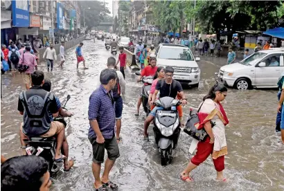  ?? PTI ?? People cross a waterlogge­d road after heavy rains in Mumbai on Wednesday. —