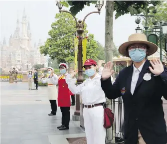  ??  ?? Park staff wearing face masks give a welcoming wave at the Disneyland theme park on Monday as it reopened in Shanghai, China. It had closed on Jan. 25 because of COVID-19.