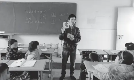  ?? PROVIDED TO CHINA DAILY ?? Village school teacher Hou Changliang uses cards with Chinese characters on them in his class at Xiangyang Primary School in Yunnan province.