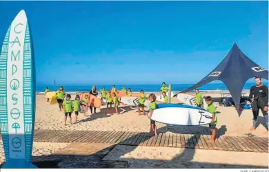  ?? SURF CAMPOSOTO ?? Los participan­tes del campamento de verano de la Escuela de Surf Camposoto portan las tablas hacia el agua.