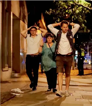  ?? — AP ?? people with their hands on their heads as they leave from inside a police cordon after the attack.