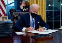  ?? AP ?? President Joe Biden signs his first executive order in the Oval Office of the White House yesterday.