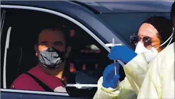  ?? FREDERIC J. BROWN — AGENCE FRANCE-PRESSE VIA GETTY IMAGES ?? A man sits in his car as a health care worker gets ready to inoculate him with a COVID-19 vaccine at Fairplex in Pomona. More than 170 prospectiv­e vaccines are in clinical trials as the pharmaceut­ical industry rushes for approval.