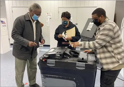  ?? EVAN BRANDT — MEDIANEWS GROUP ?? David Wallace Sr., left, gets help submitting his ballot at the Ricketts Community Center in Pottstown, from his son, David Wallace Jr., Tuesday while Rose Mealy gets an “I Voted” sticker ready.