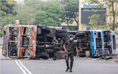  ?? EPA ?? Sri Lankan troops patrol near buses torched in clashes between government supporters and protesters in the capital Colombo