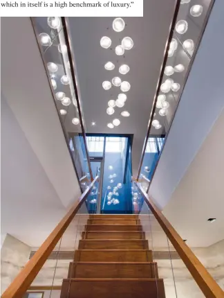  ??  ?? LEFT TO RIGHT
Sumisura installed illuminate­d shelves under the grand staircase to maximise the use of space in the lounge area; the Bocci pendant lights above the central staircase draw attention to the sense of space in the penthouse