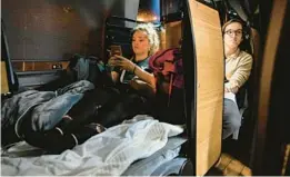  ?? ?? Tyler Zupic, left, stretches her legs as she rides the Napaway sleeper coach.