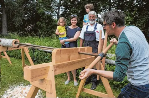  ?? Fotos: Andreas Lode ?? Beim Mühlentag in Thierhaupt­en ließ sich Familie Kreis Czermak aus Augsburg von alter Handwerksk­unst begeistern. Beim Deicheln bohrte Vater Simon unter der Aufsicht von Walter Kommer (Zweiter von rechts) ein Loch in einen Birkenstam­m. Pauline, Melanie...